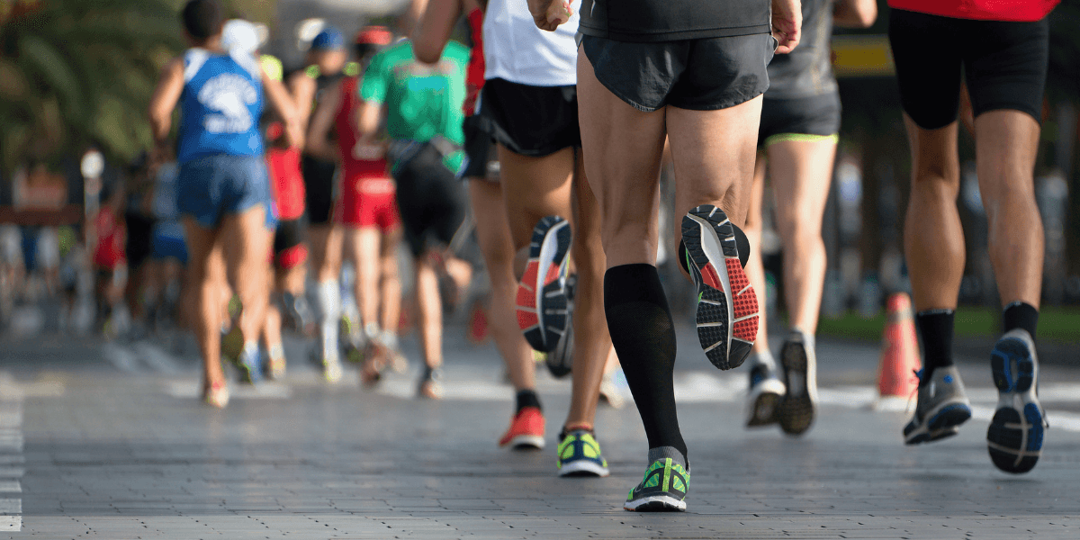 Runners participate in a race on a paved pathway lined with trees