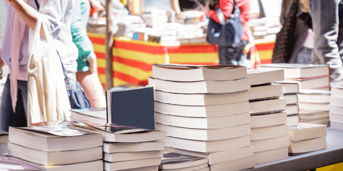 Stacks of books on a table at a vibrant outdoor market
