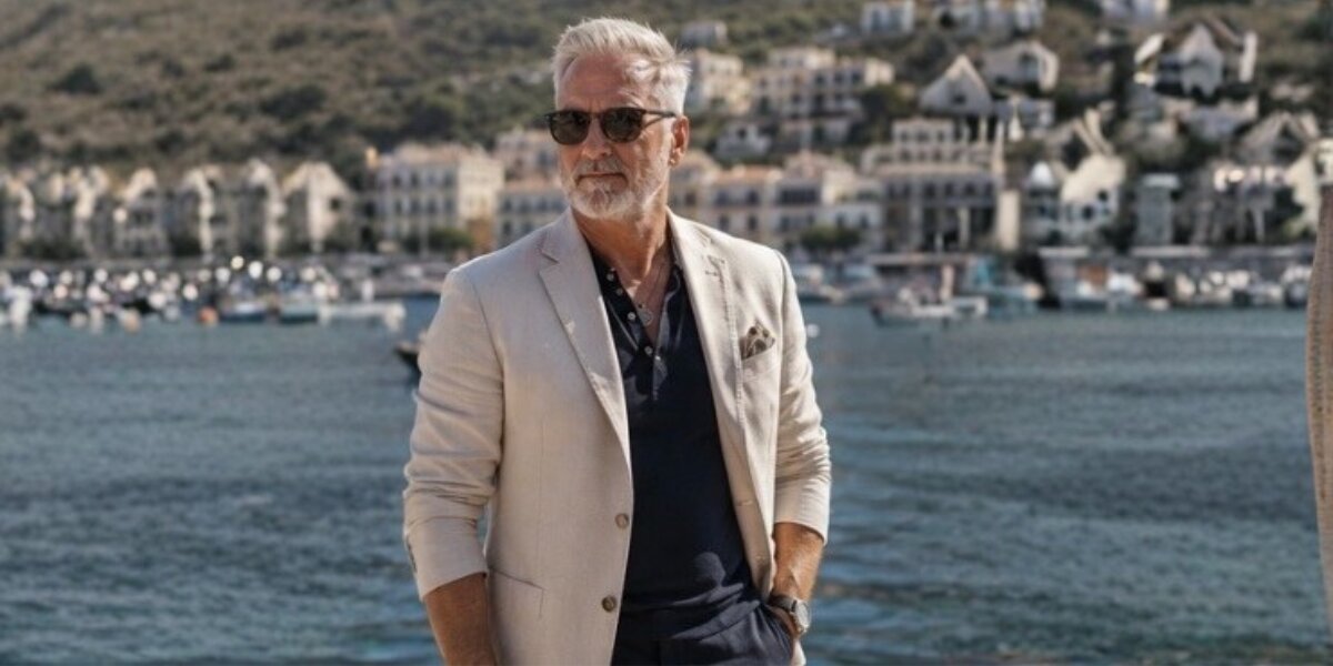 Richard Knight standing at a waterfront marina, wearing a light blazer and sunglasses, representing his professional Tarot teaching brand.