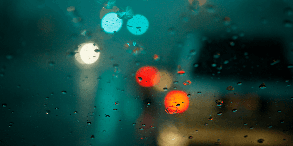 Raindrops on a car window with blurred colorful lights in the background