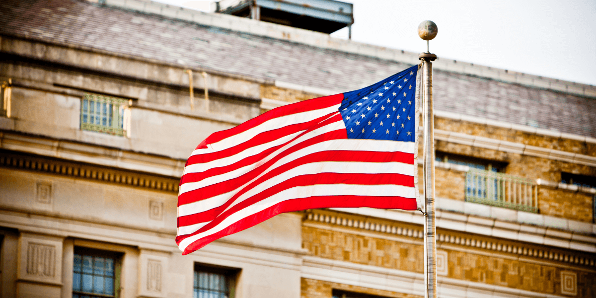 Waving American flag in front of a building with a historic design