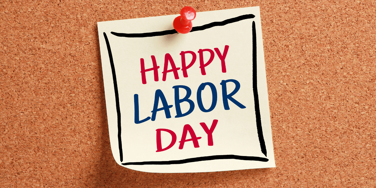 Sticky note on corkboard with the text "Happy Labor Day" in red and blue letters