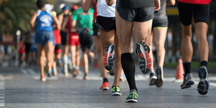 Runners participate in a race on a paved pathway lined with trees