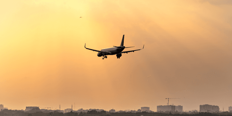 Airplane approaching landing during a sunset with rays of light illuminating the sky
