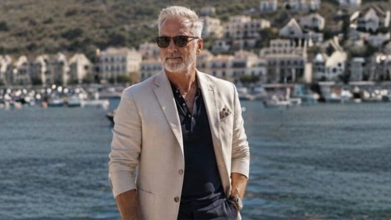 Richard Knight standing at a waterfront marina, wearing a light blazer and sunglasses, representing his professional Tarot teaching brand.
