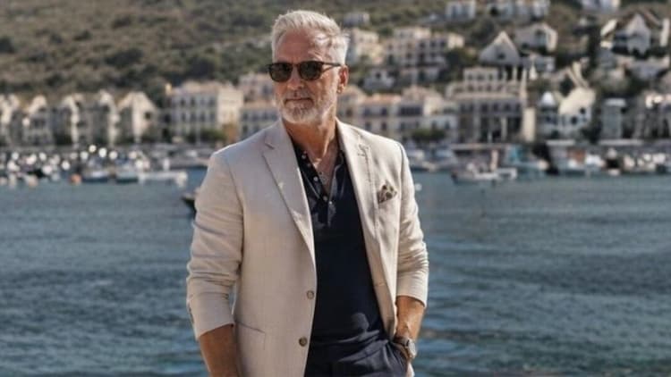 Richard Knight standing at a waterfront marina, wearing a light blazer and sunglasses, representing his professional Tarot teaching brand.