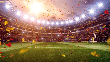 FIFA World Cup trophy beside a soccer ball on a grass field.