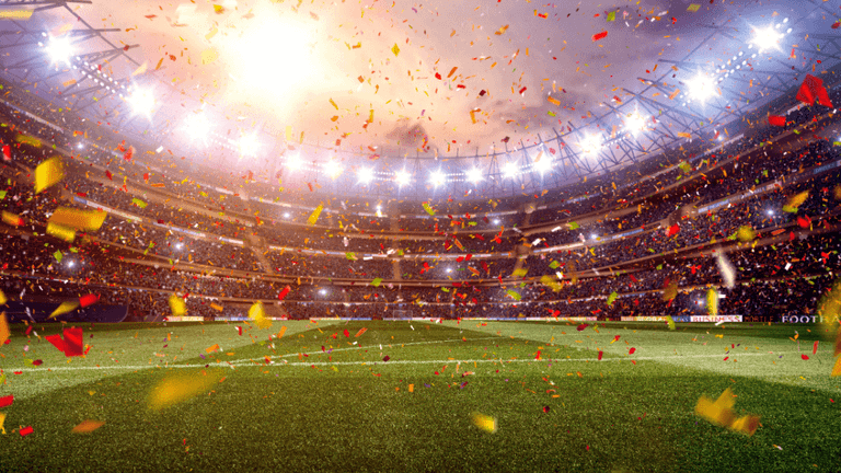 FIFA World Cup trophy beside a soccer ball on a grass field.