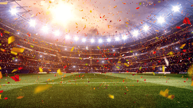 FIFA World Cup trophy beside a soccer ball on a grass field.