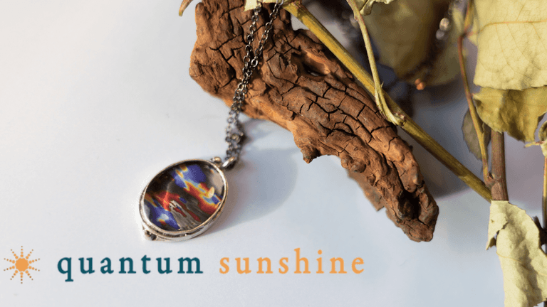 The image depicts a Quantum Sunshine pendant featuring a scientific design, blending art and science for meaningful, wearable art.