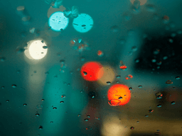 Raindrops on a car window with blurred colorful lights in the background