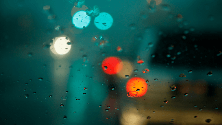 Raindrops on a car window with blurred colorful lights in the background