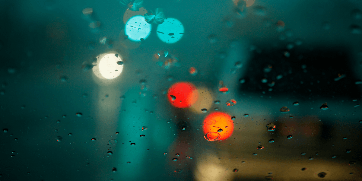 Raindrops on a car window with blurred colorful lights in the background