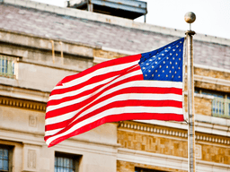 Waving American flag in front of a building with a historic design