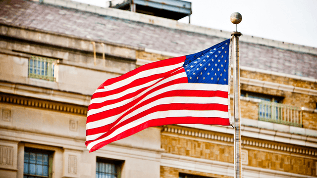 Waving American flag in front of a building with a historic design