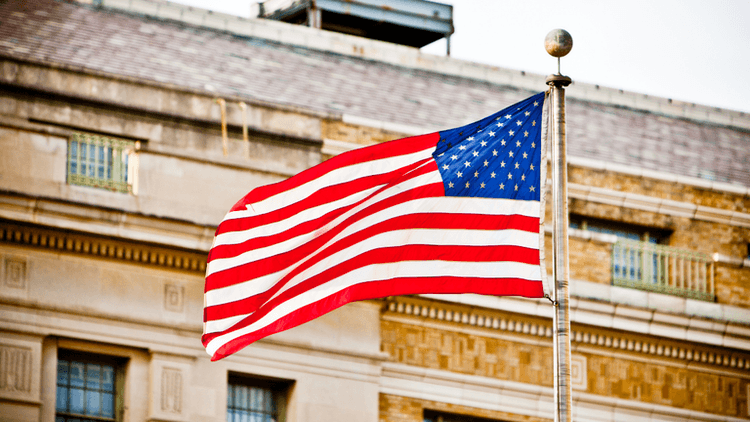 Waving American flag in front of a building with a historic design