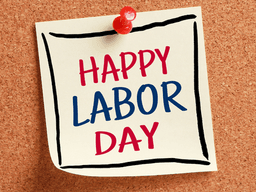 Sticky note on corkboard with the text "Happy Labor Day" in red and blue letters