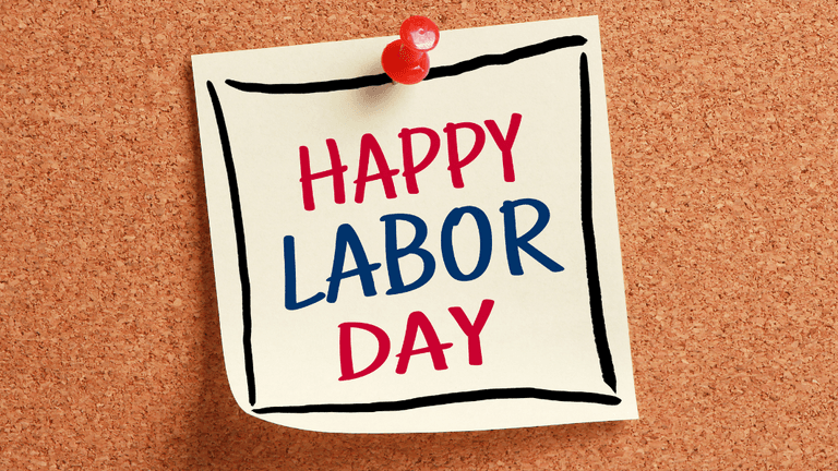 Sticky note on corkboard with the text "Happy Labor Day" in red and blue letters