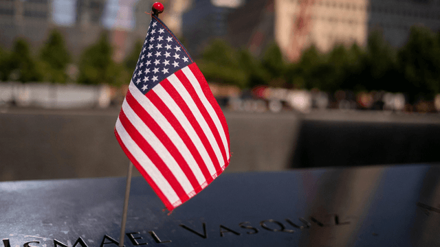Small American flag next to a name on a memorial plaque in remembrance.