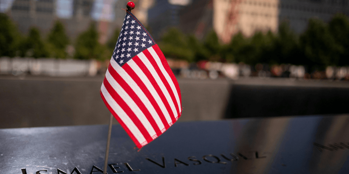 Small American flag next to a name on a memorial plaque in remembrance.