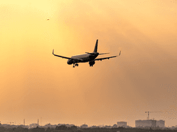 Airplane approaching landing during a sunset with rays of light illuminating the sky