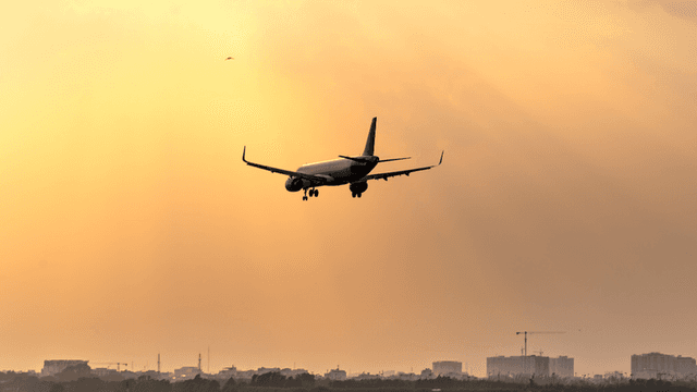 Airplane approaching landing during a sunset with rays of light illuminating the sky