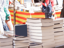 Stacks of books on a table at a vibrant outdoor market