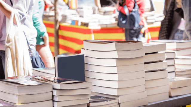 Stacks of books on a table at a vibrant outdoor market