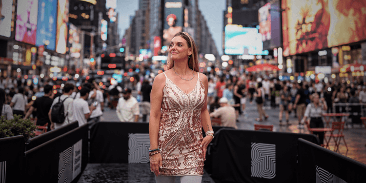 Woman in a sparkling dress standing in a crowded Times Square at dusk