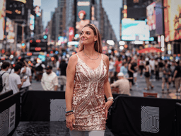 Woman in a sparkling dress standing in a crowded Times Square at dusk