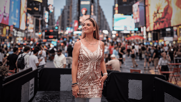 Woman in a sparkling dress standing in a crowded Times Square at dusk