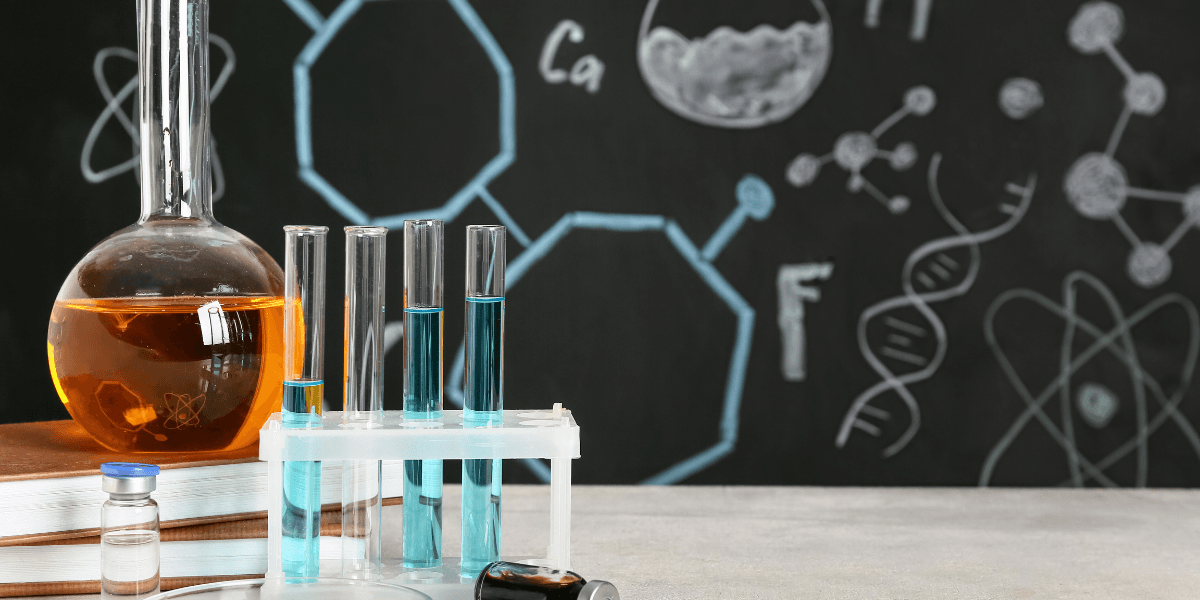Laboratory setup with test tubes, a flask, and a chalkboard with chemical diagrams