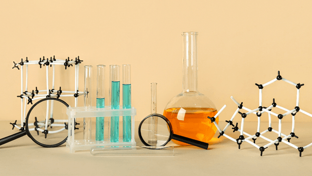 Laboratory glassware and molecular models arranged artistically against a neutral background