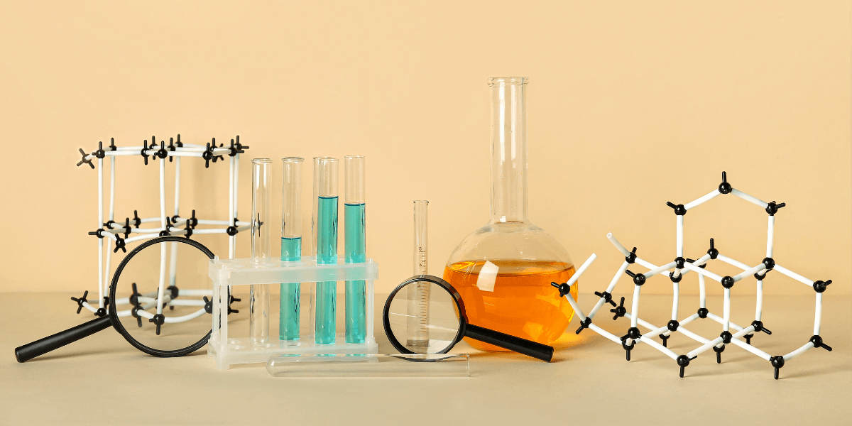 Laboratory glassware and molecular models arranged artistically against a neutral background
