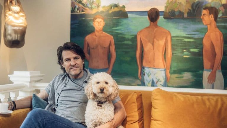 A man sits on a couch with his dog, enjoying a relaxed moment together in a cozy living room setting.