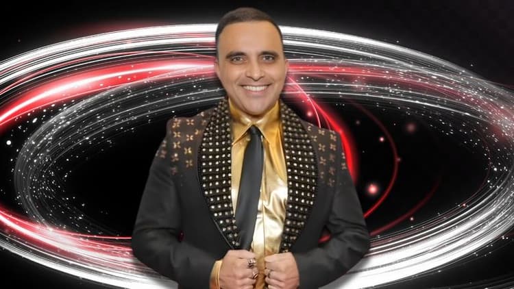 Smiling man in a studded black suit and gold shirt stands confidently. Behind him, swirls of red and white lights create a dynamic, energetic backdrop.