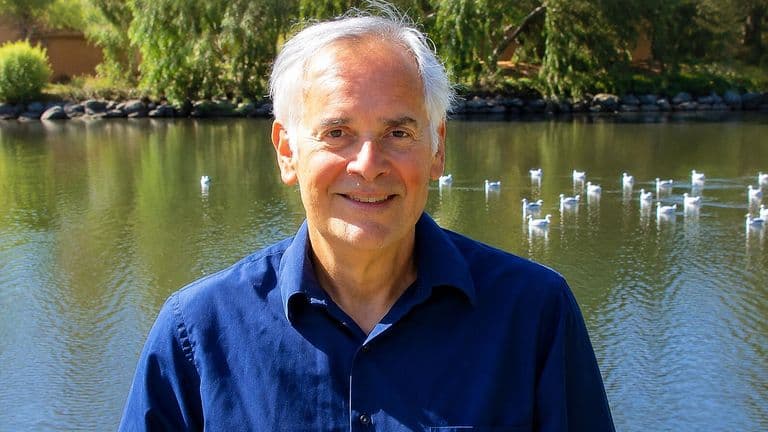 Ron Feldman smiling beside a lakeside pond, reflecting on resilience, personal growth, and his bridge career.