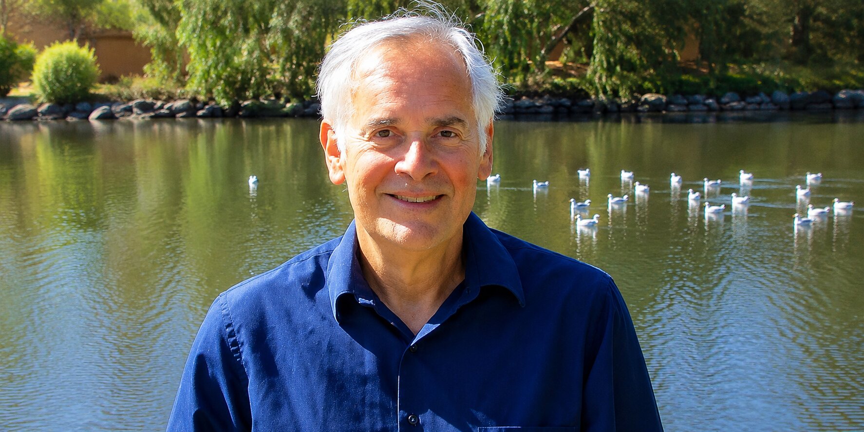 Ron Feldman smiling beside a lakeside pond, reflecting on resilience, personal growth, and his bridge career.