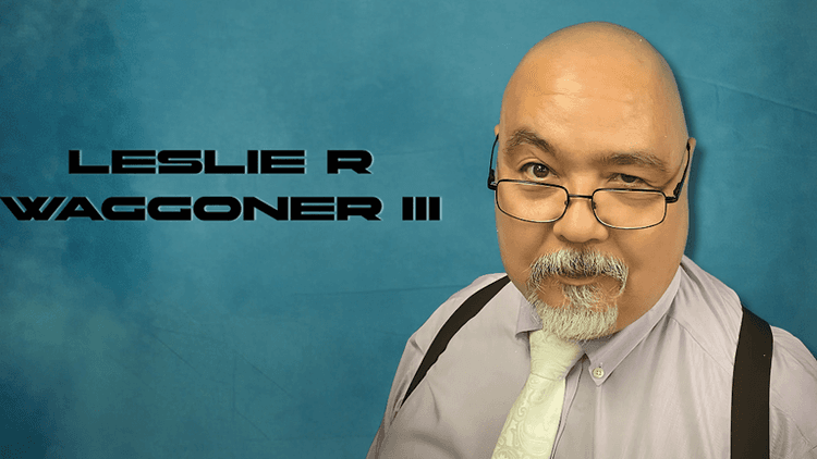 "Portrait of author Leslie R. Waggoner III, dressed in a purple shirt with a tie, sporting glasses and a beard, set against a blue background."