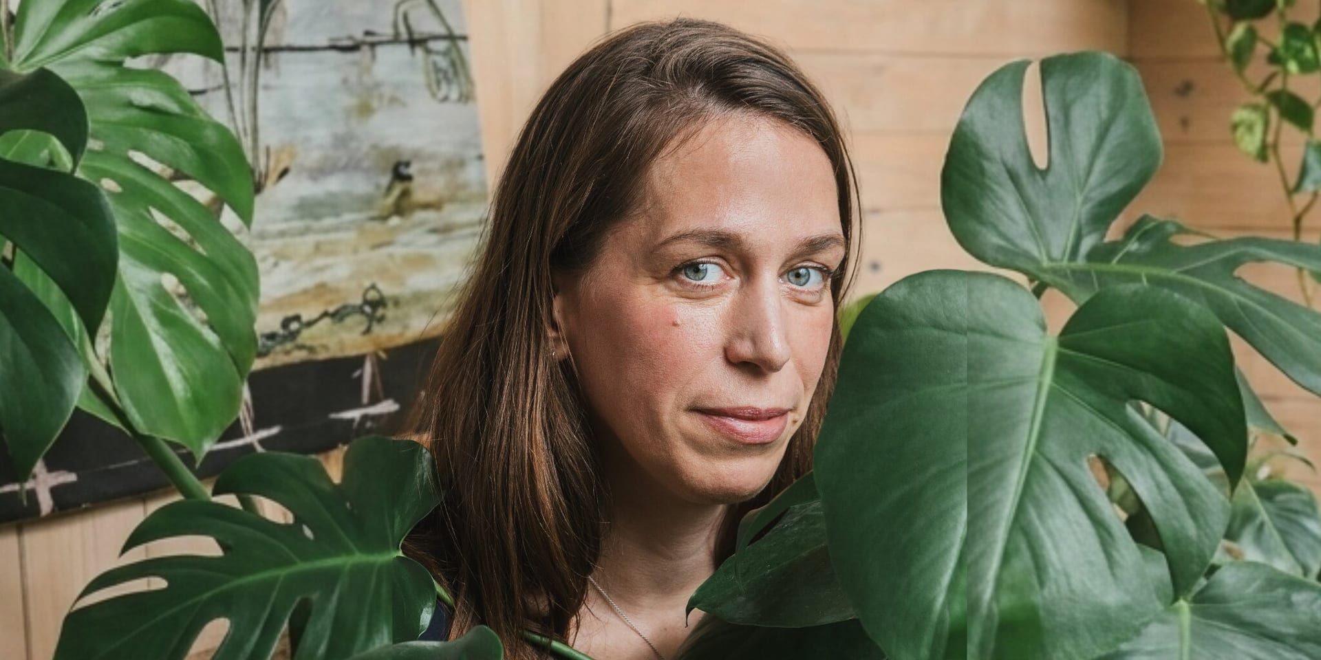 Portrait of artist Laila Seidel surrounded by large green leaves.