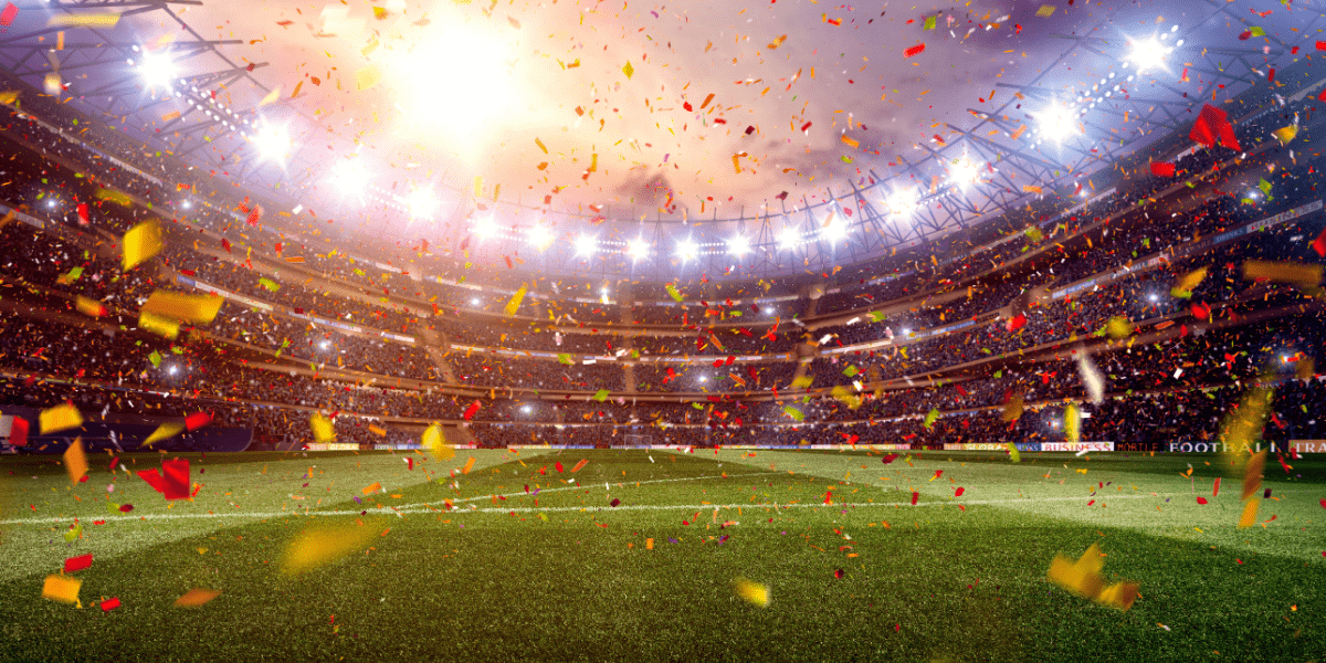 FIFA World Cup trophy beside a soccer ball on a grass field.