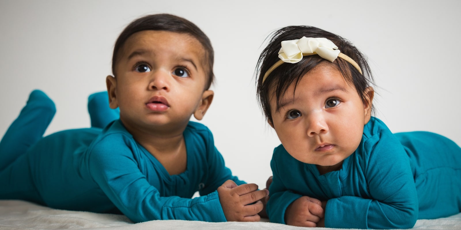 Two babies in matching teal outfits, symbolizing Tiny Culture's mission to celebrate cultural identity through baby fashion.