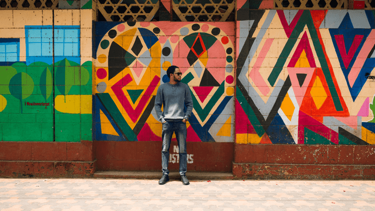 Man stands in front of colorful geometric mural, symbolizing innovation and clarity in digital financial data.