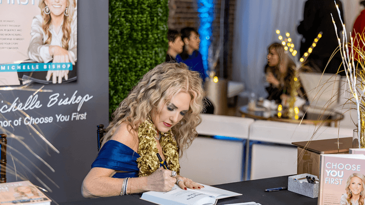 Michelle Bishop signs books at an event, promoting her empowerment journey and message from her bestseller "Choose You First."