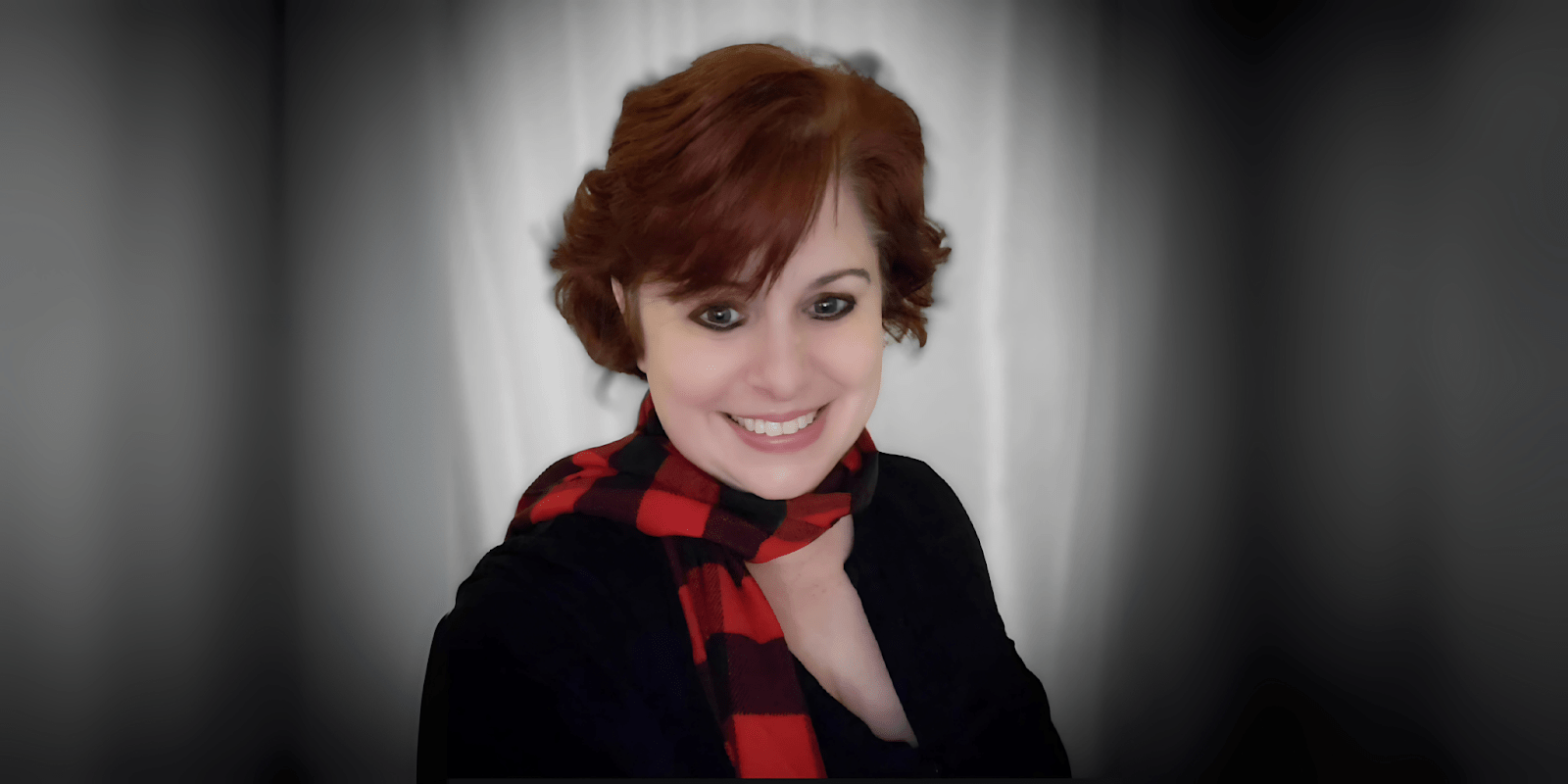Tempie W. Wade smiling with a red and black checkered scarf against a neutral background.