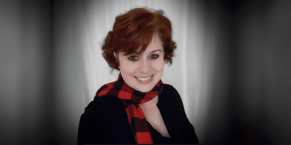 Tempie W. Wade smiling with a red and black checkered scarf against a neutral background.