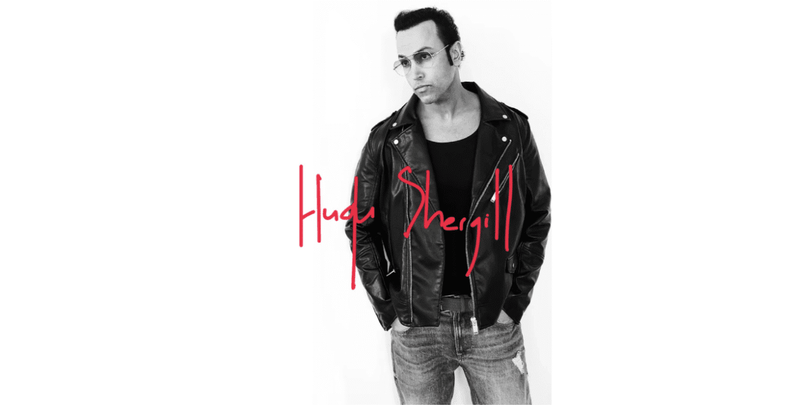 "Black and white portrait of Hugh Shergill wearing a leather jacket and sunglasses with a red handwritten signature of his name, Hugh Shergill, below the image."