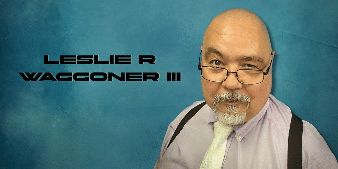 "Portrait of author Leslie R. Waggoner III, dressed in a purple shirt with a tie, sporting glasses and a beard, set against a blue background."