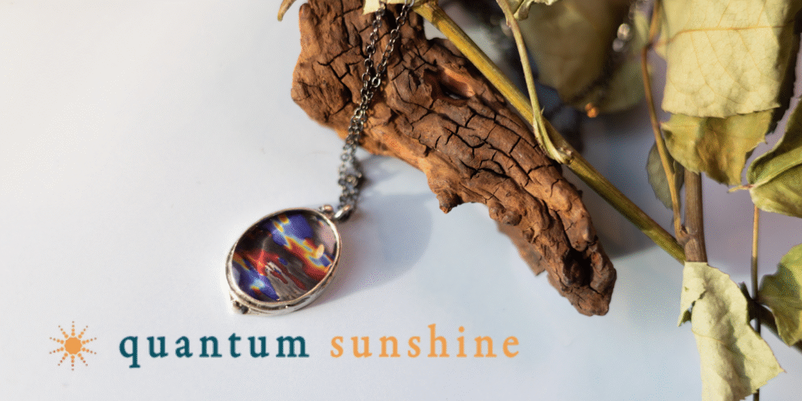 The image depicts a Quantum Sunshine pendant featuring a scientific design, blending art and science for meaningful, wearable art.