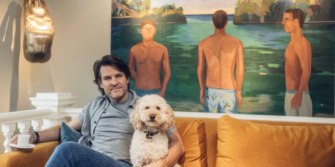 A man sits on a couch with his dog, enjoying a relaxed moment together in a cozy living room setting.